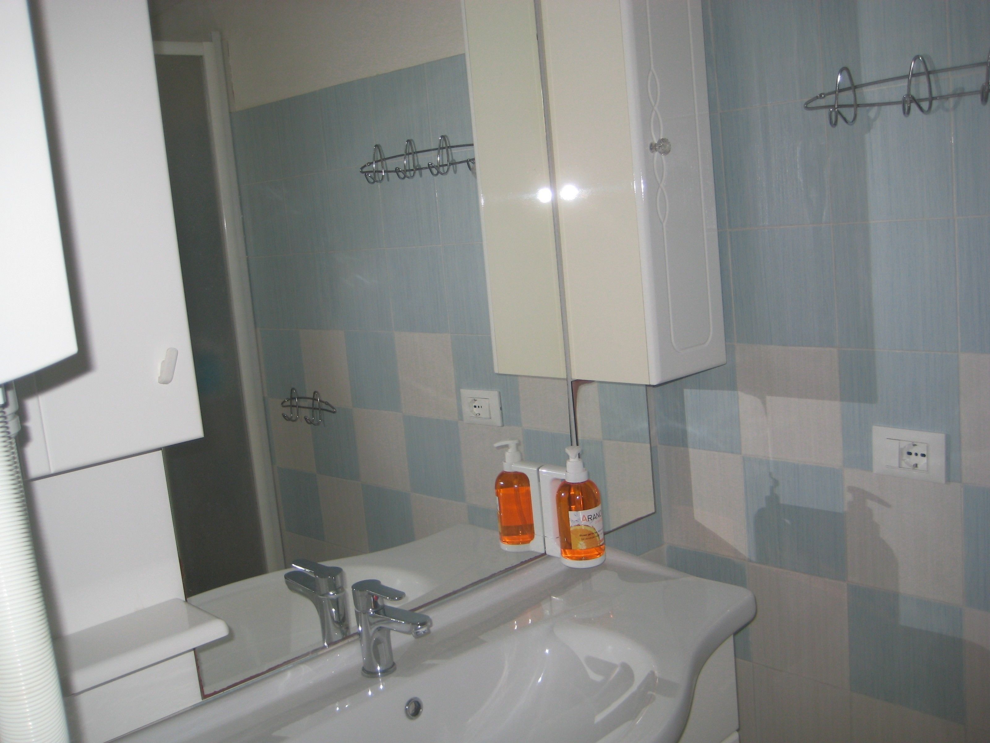 A bathroom with a sink, mirror, and two bottles of hand soap.