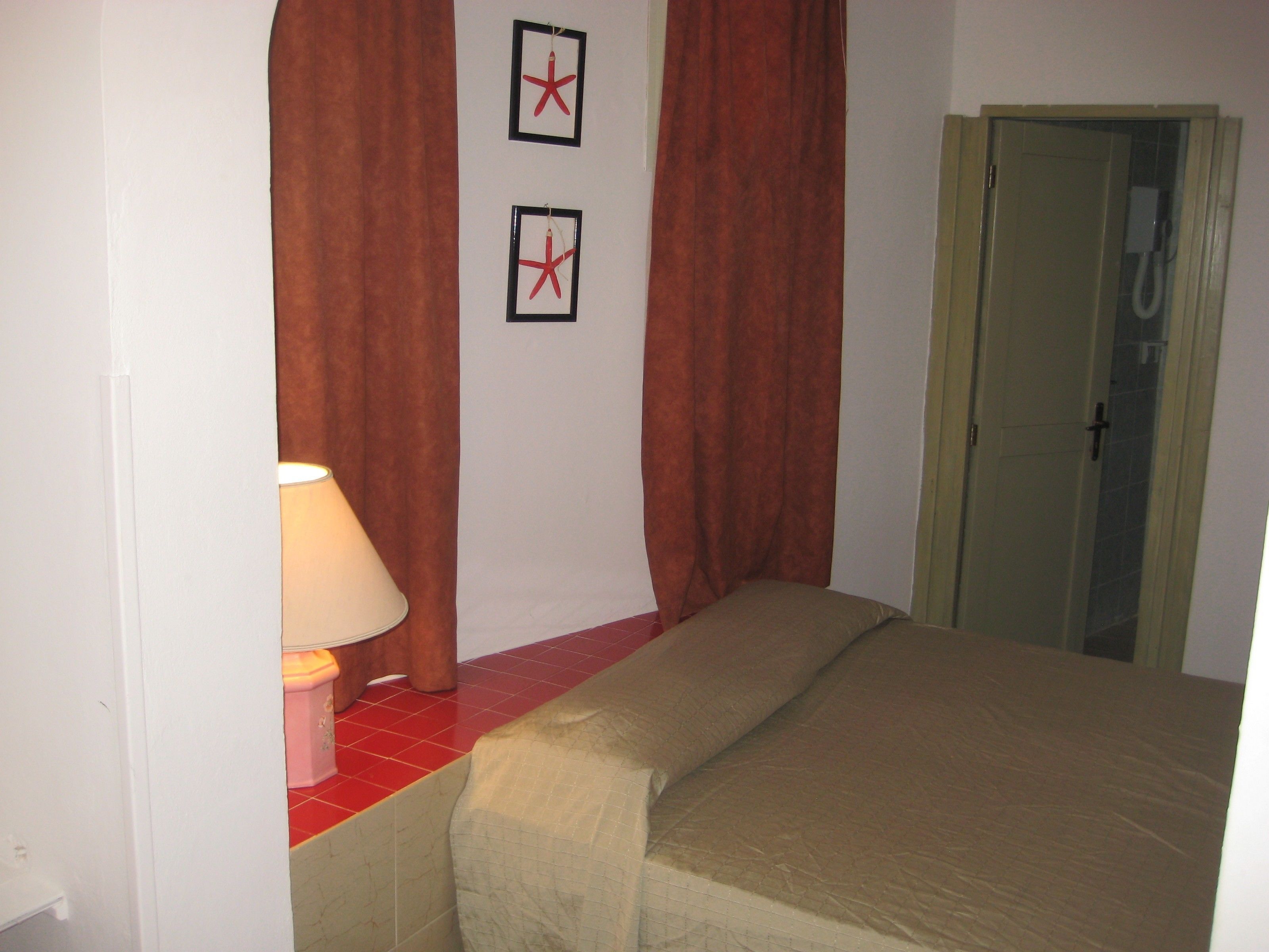 A hotel room with a bed, a lamp, and a shower door.