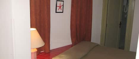 A hotel room with a bed, a lamp, and a shower door.