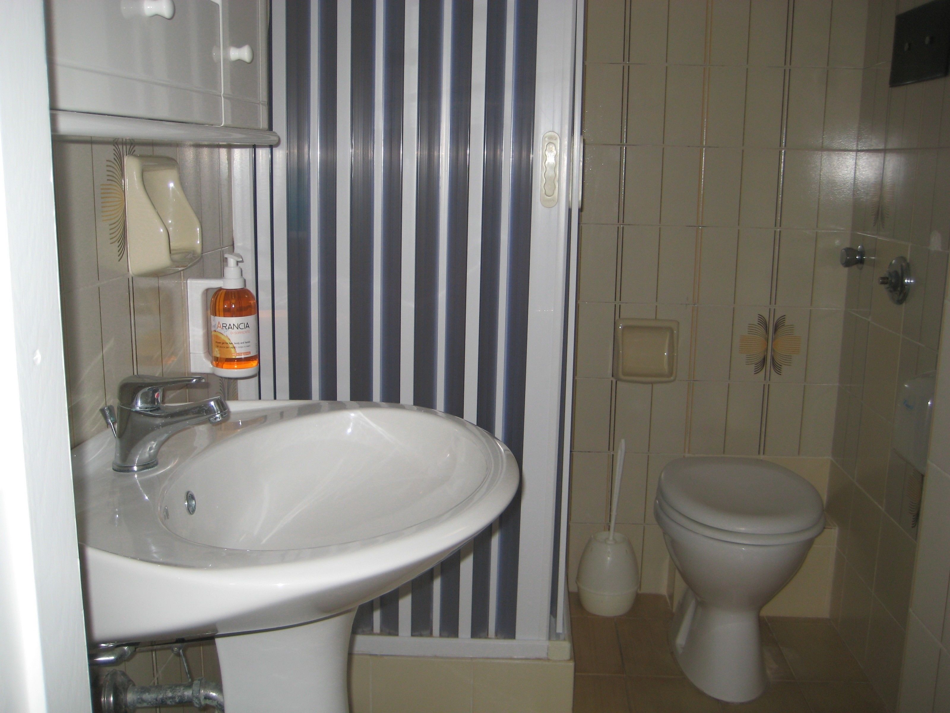 A bathroom with a white sink, a toilet, and a striped wall.