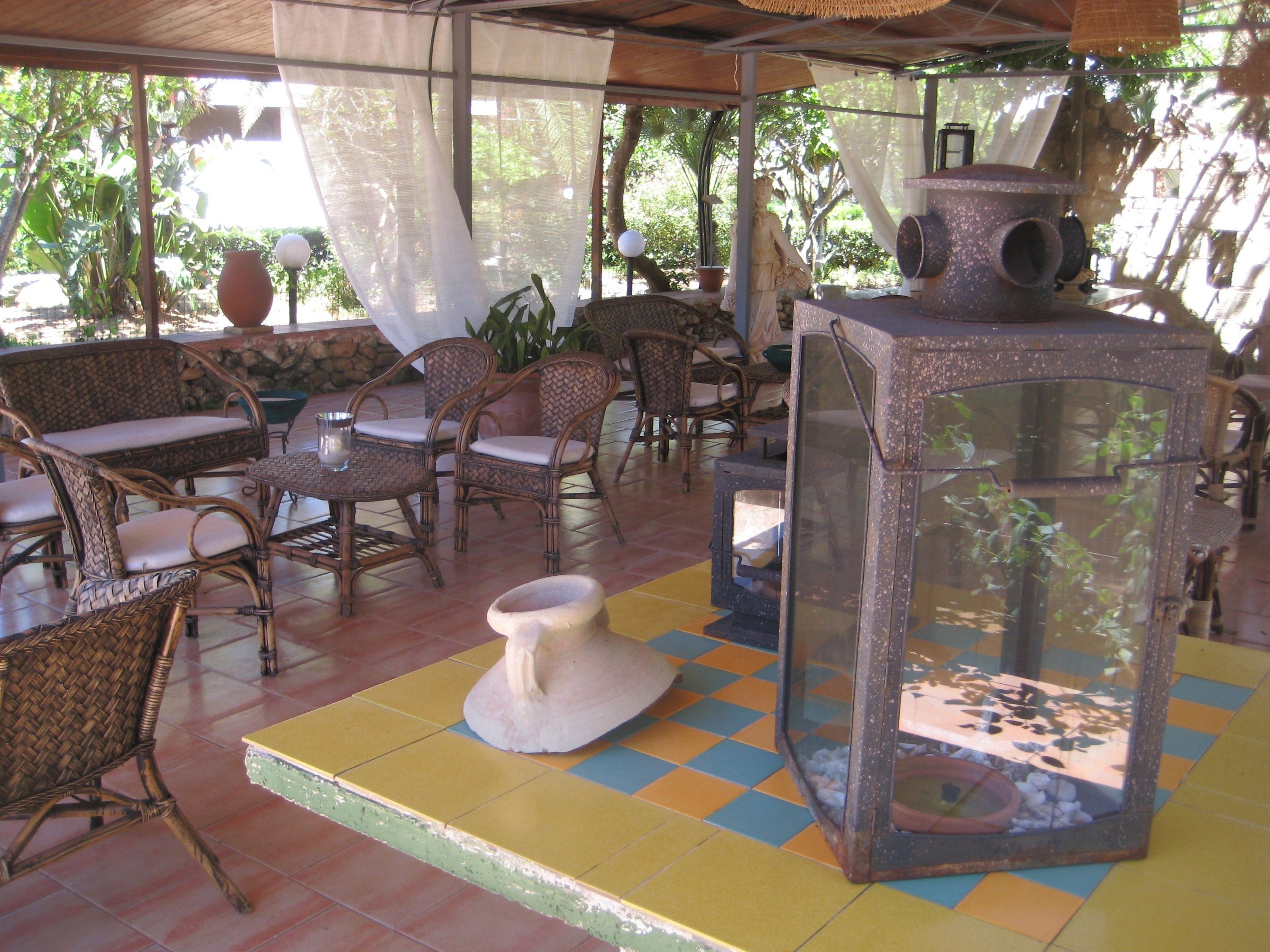 A covered outdoor seating area with wicker furniture and a glass-top table.