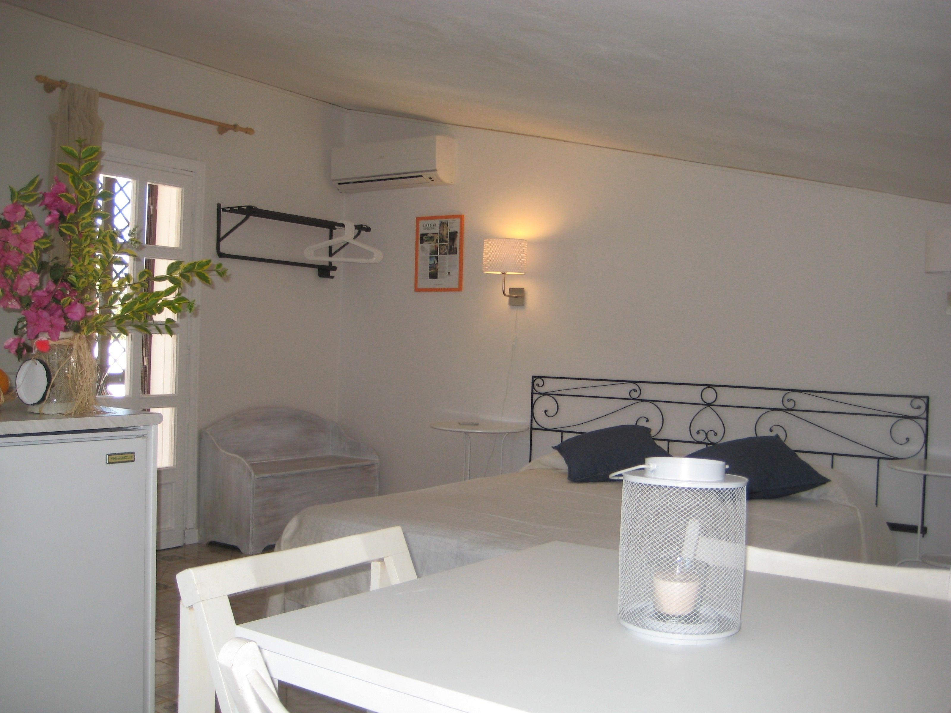 A bedroom with a bed, bedside table, and a small table with a candle.
