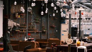 A modern interior with sofas, a dining table, and a robot. - Shaoxing Luxun Native Place Youth Hostel (Shaoxing)