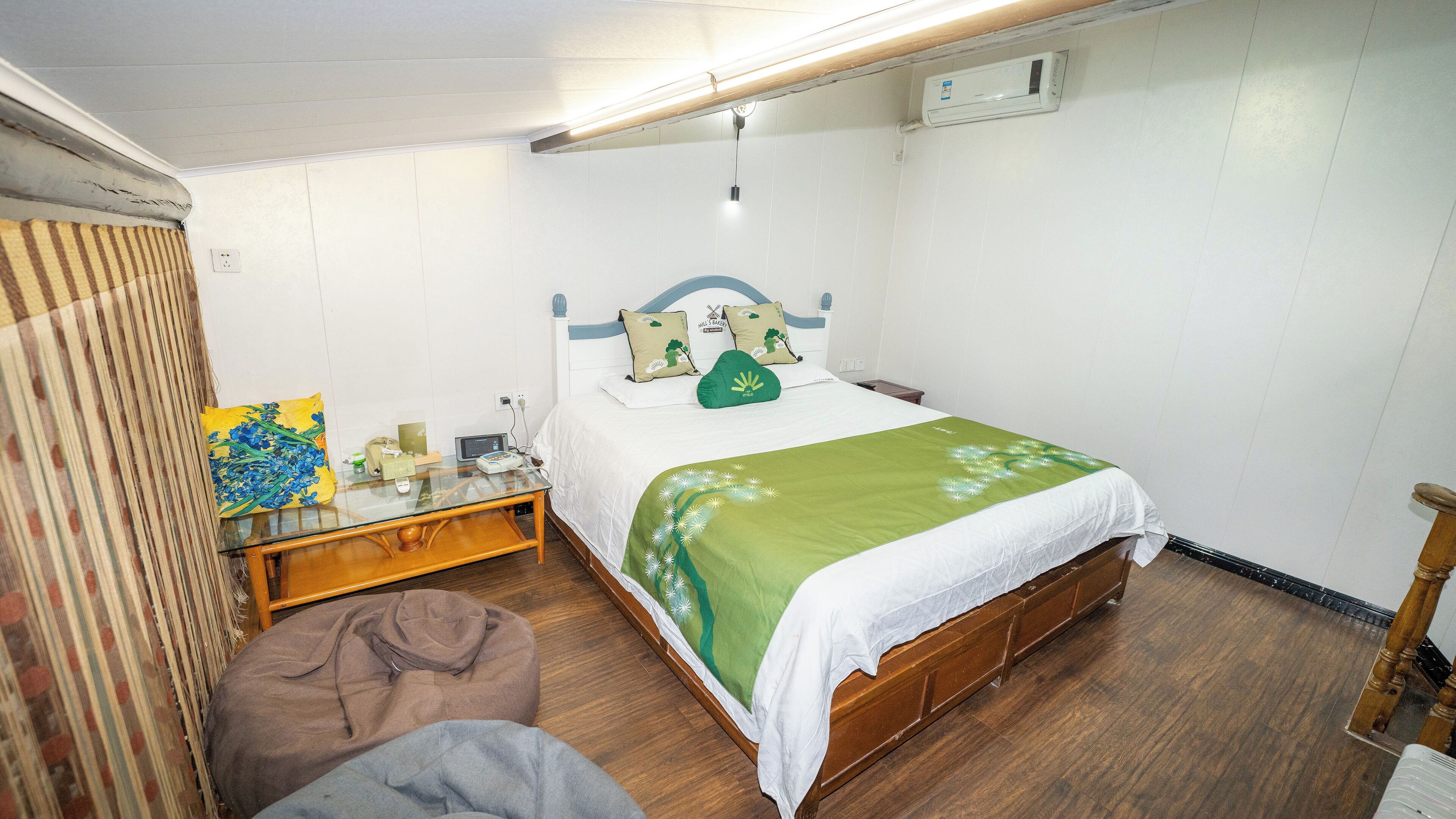 Un dormitorio compacto con una cama individual, una mesita de noche, una lámpara y un taburete pequeño.
