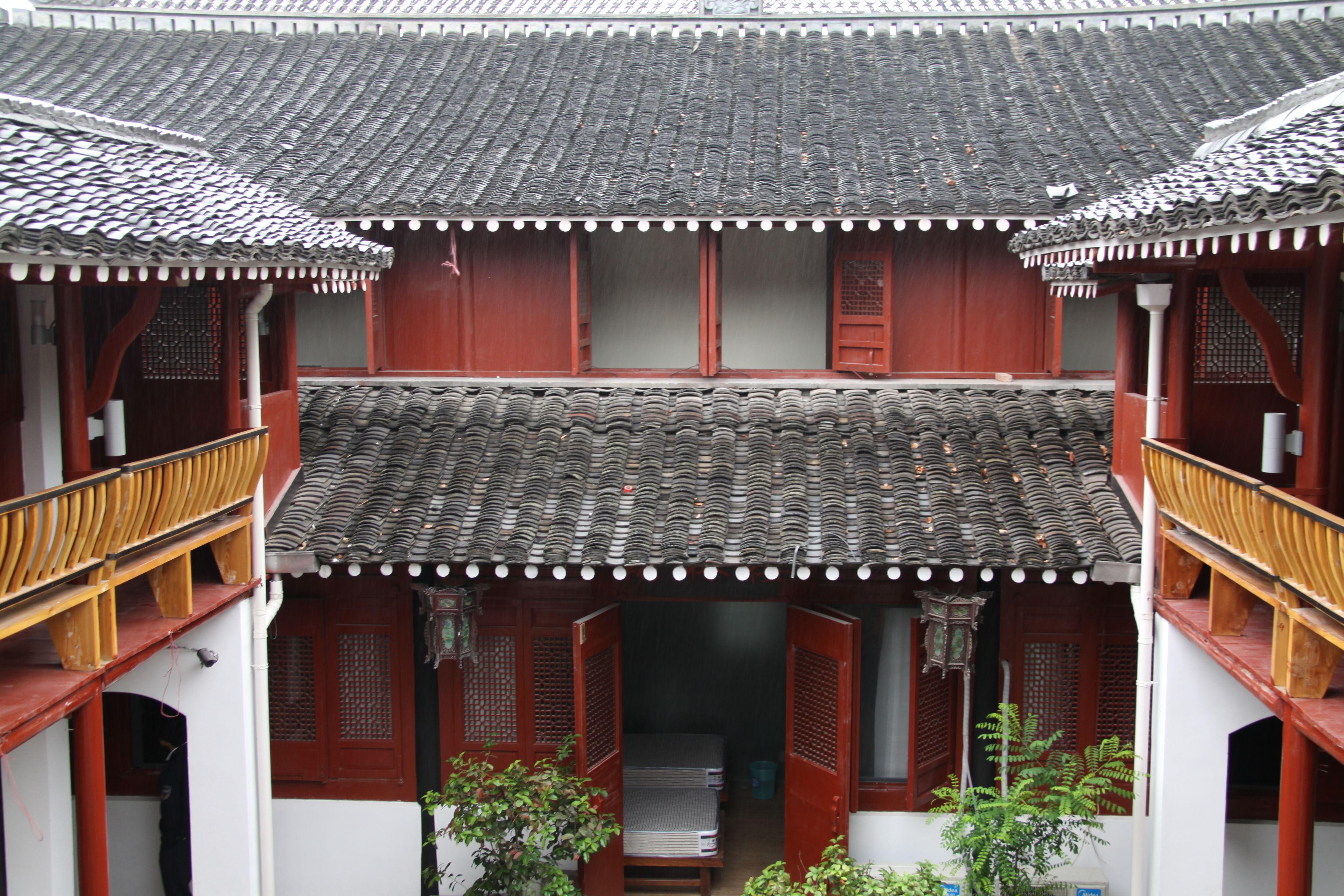 Un edificio tradicional con techo de tejas, balcones de madera y puertas rojas.