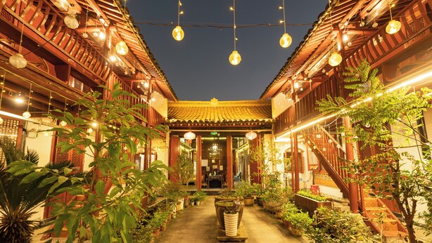 A traditional courtyard with potted plants, wooden buildings, and hanging lights. - Shaoxing Luxun Native Place Youth Hostel (Shaoxing)