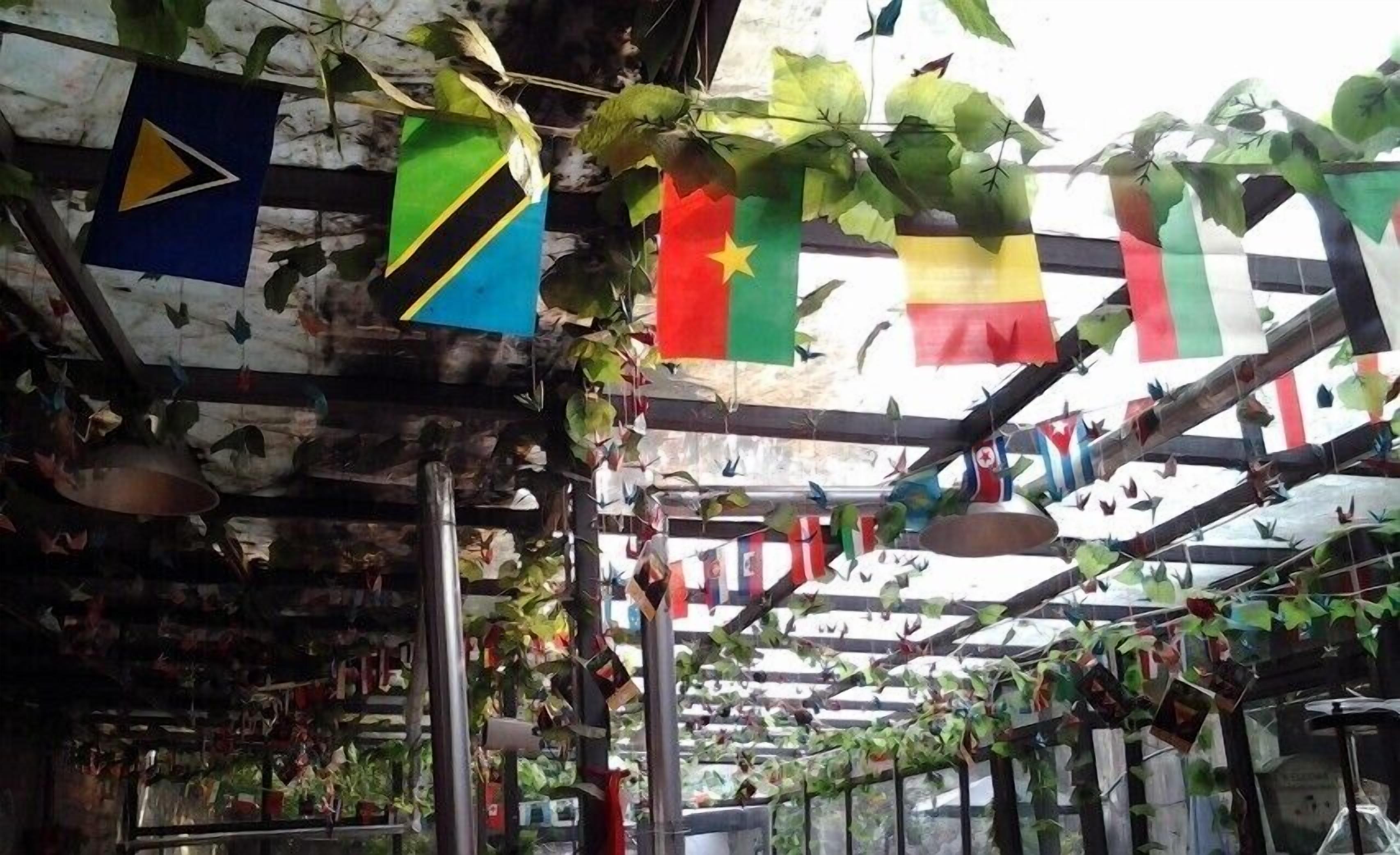 A greenhouse with various plants and hanging flags.