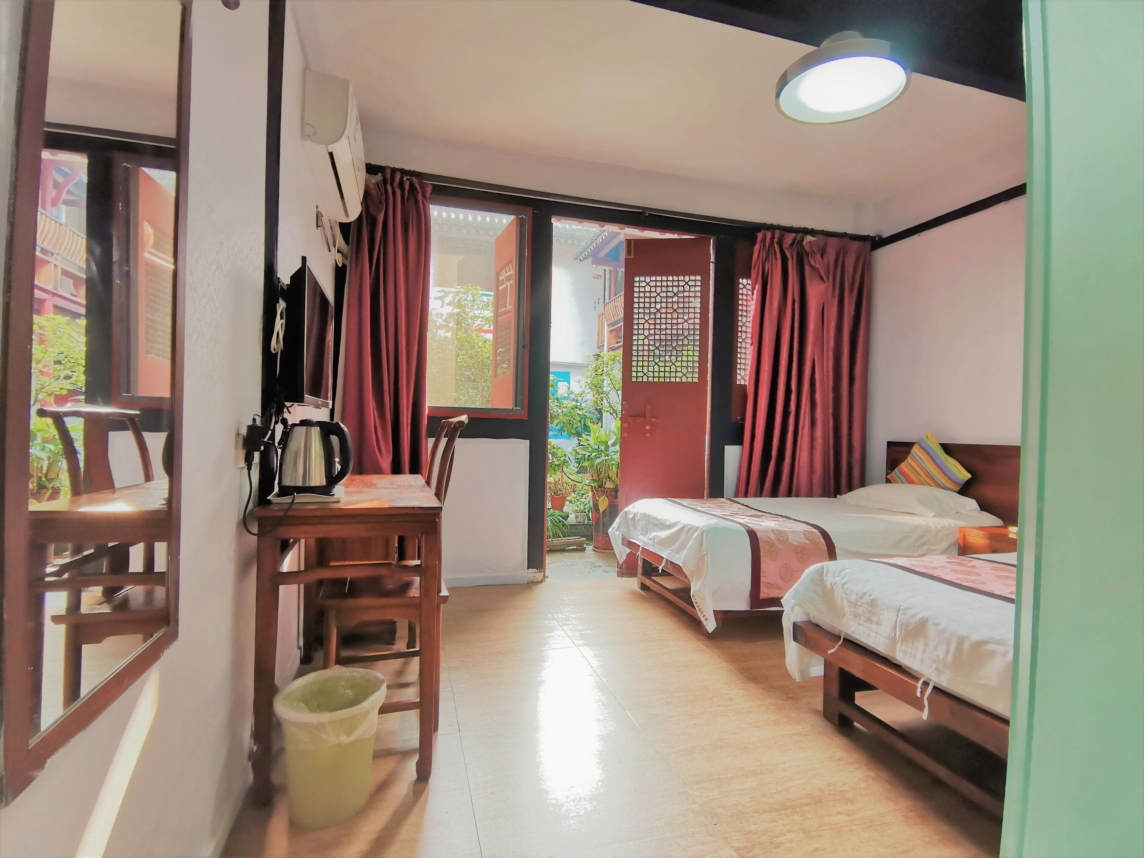 Una habitación de hotel con un escritorio de madera, una cama, una silla y un pequeño cubo de basura.