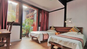 A room with two beds, a wooden table, and a view of a traditional building outside. - Shaoxing Luxun Native Place Youth Hostel (Shaoxing)