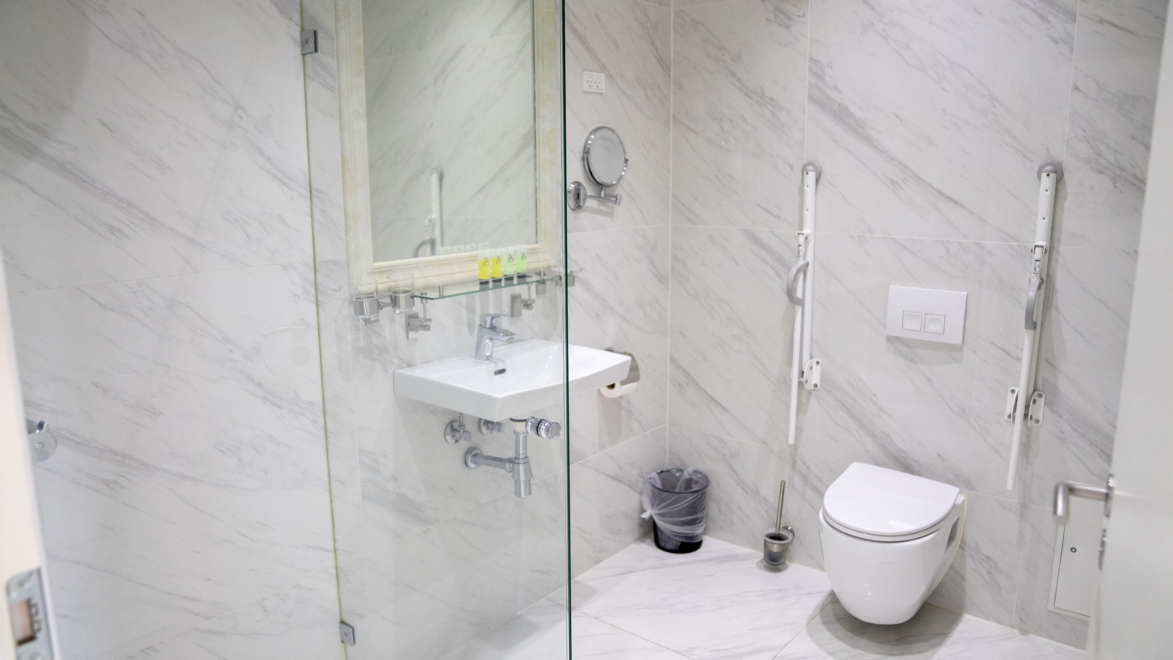A modern bathroom with a glass-enclosed shower, a white sink, and a toilet.
