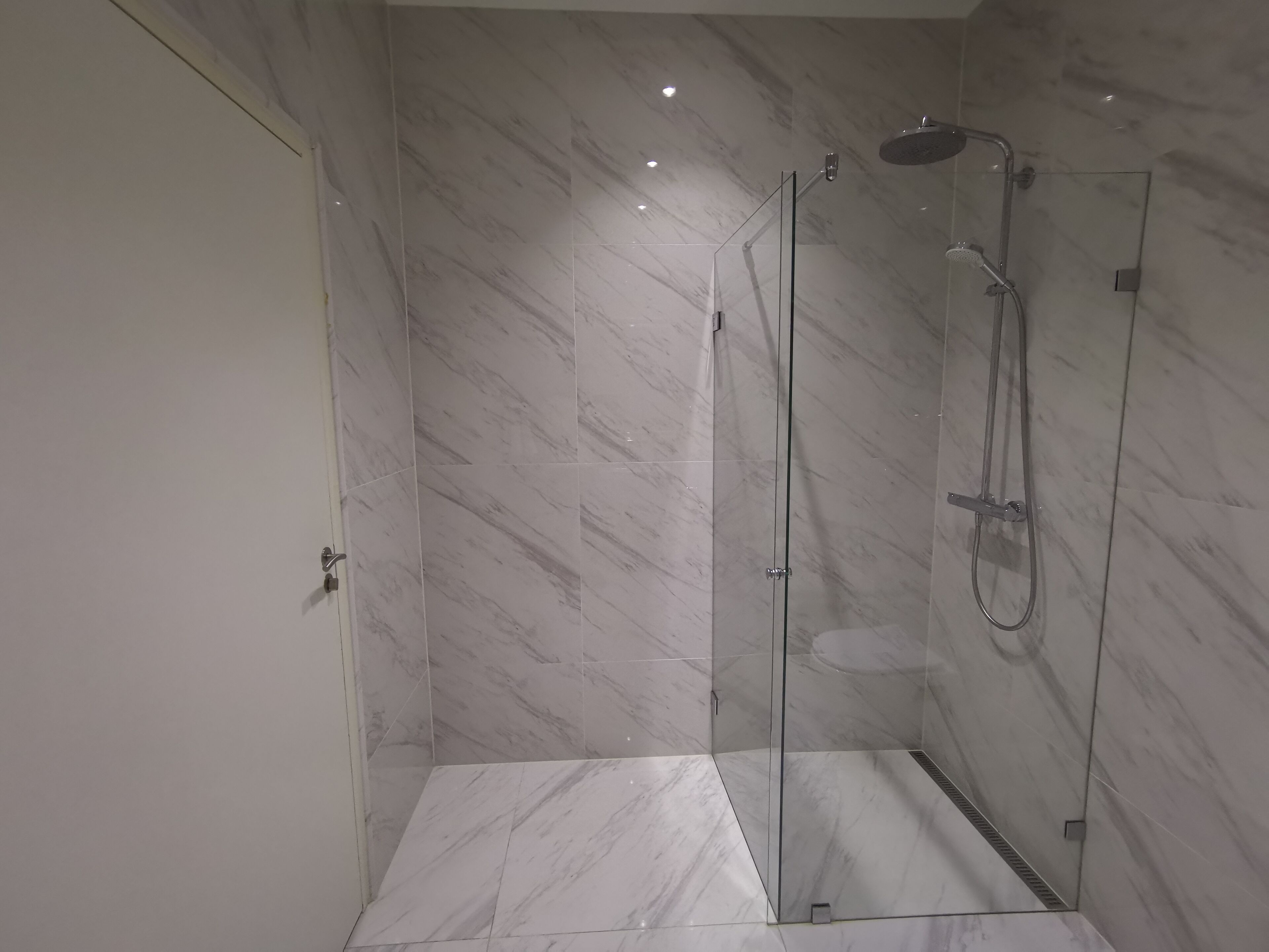 A modern shower area with glass doors and a rain shower head.