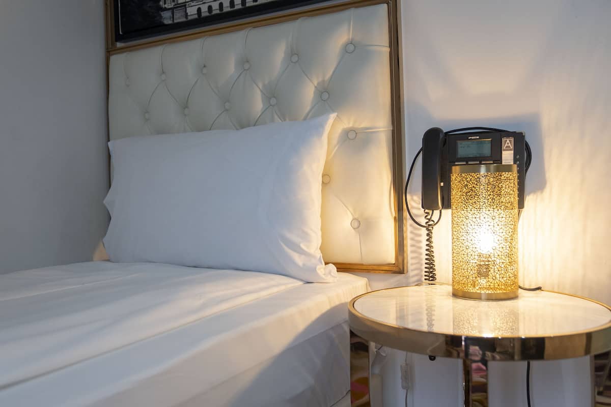 A hotel room with a bed, a bedside table, and a lamp.