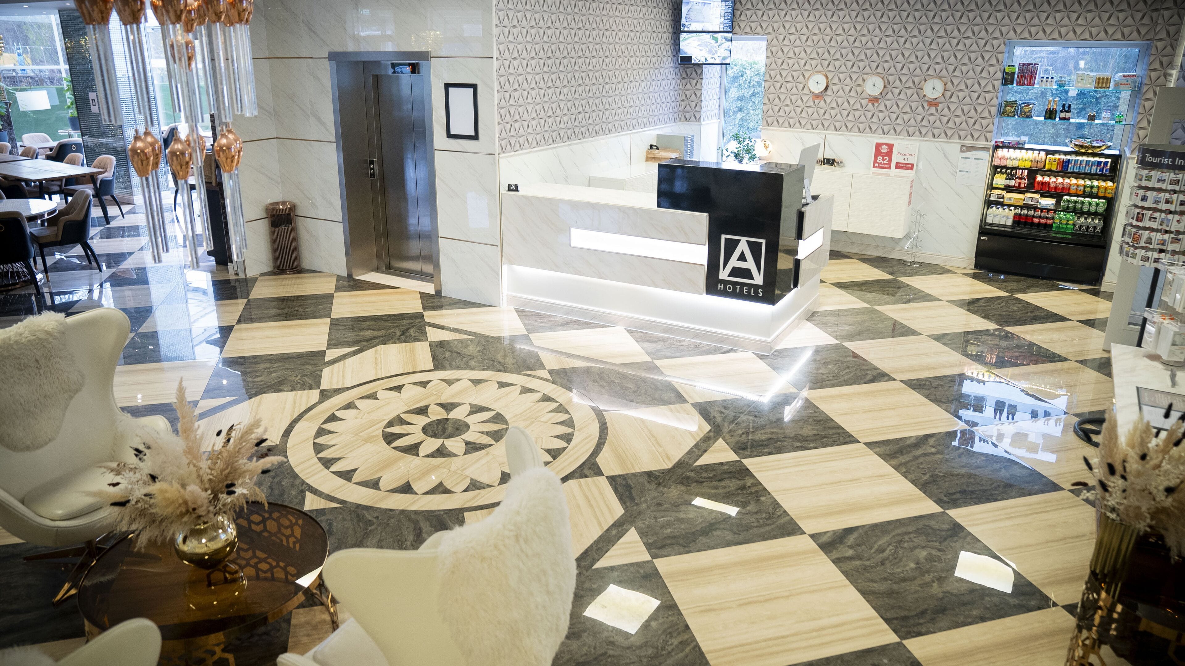 Un vestíbulo de hotel con mostrador de recepción, área de espera y mesas y sillas.