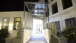 A building entrance with a glass canopy, two lion statues, and potted plants. - A Hotels Glostrup (Brondby)