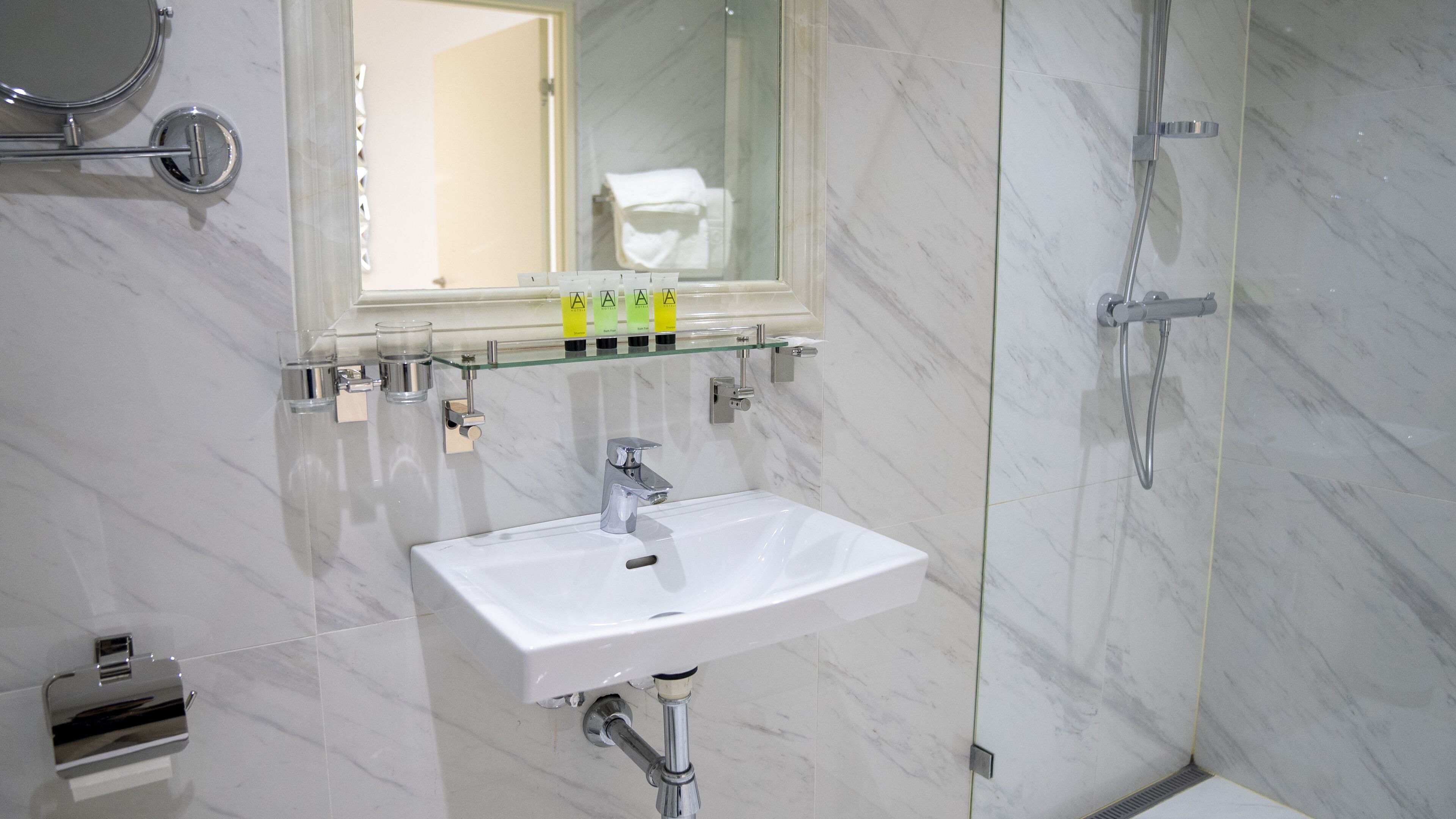 Une salle de bain moderne avec un lavabo blanc, une douche en verre et un miroir au-dessus du lavabo.