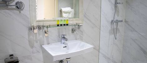 Une salle de bain moderne avec un lavabo blanc, une douche en verre et un miroir au-dessus du lavabo.