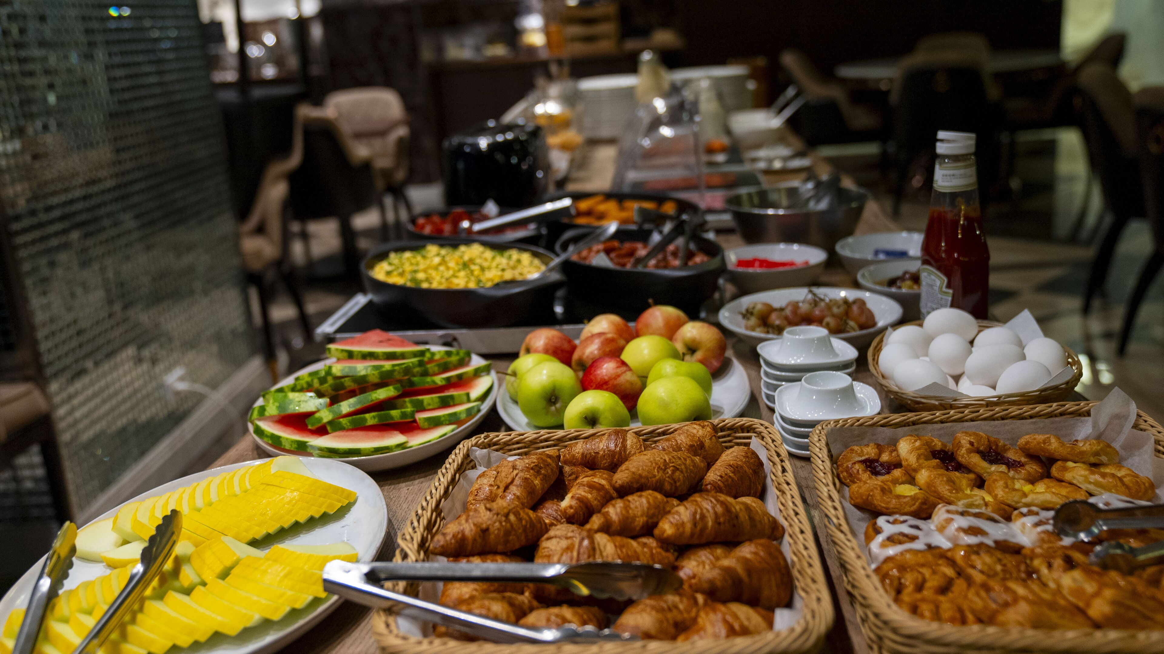 Un buffet proposant une variété de plats, notamment des fruits, des pâtisseries et des plats pour le petit-déjeuner.