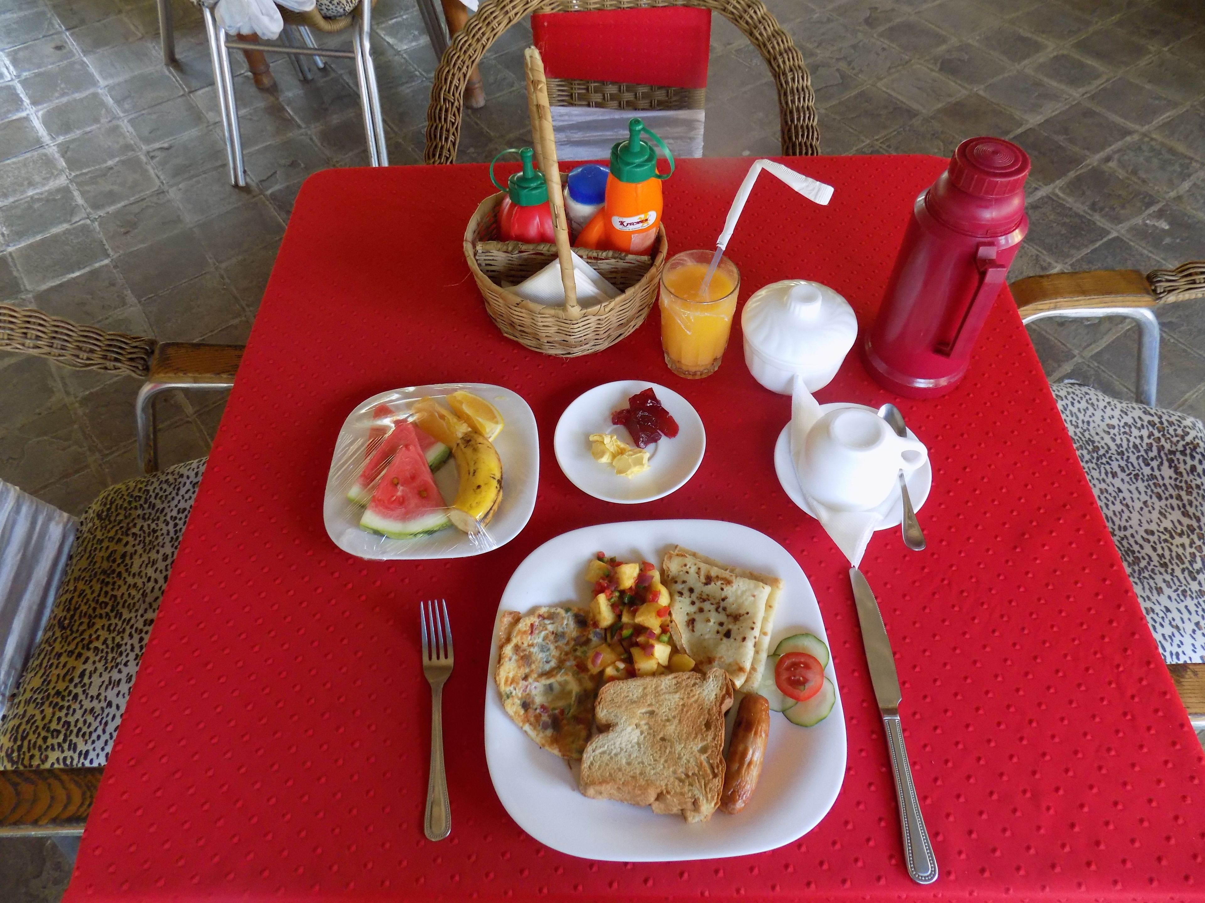 Uma mesa de café da manhã com pratos de comida, uma cesta e acompanhamentos.