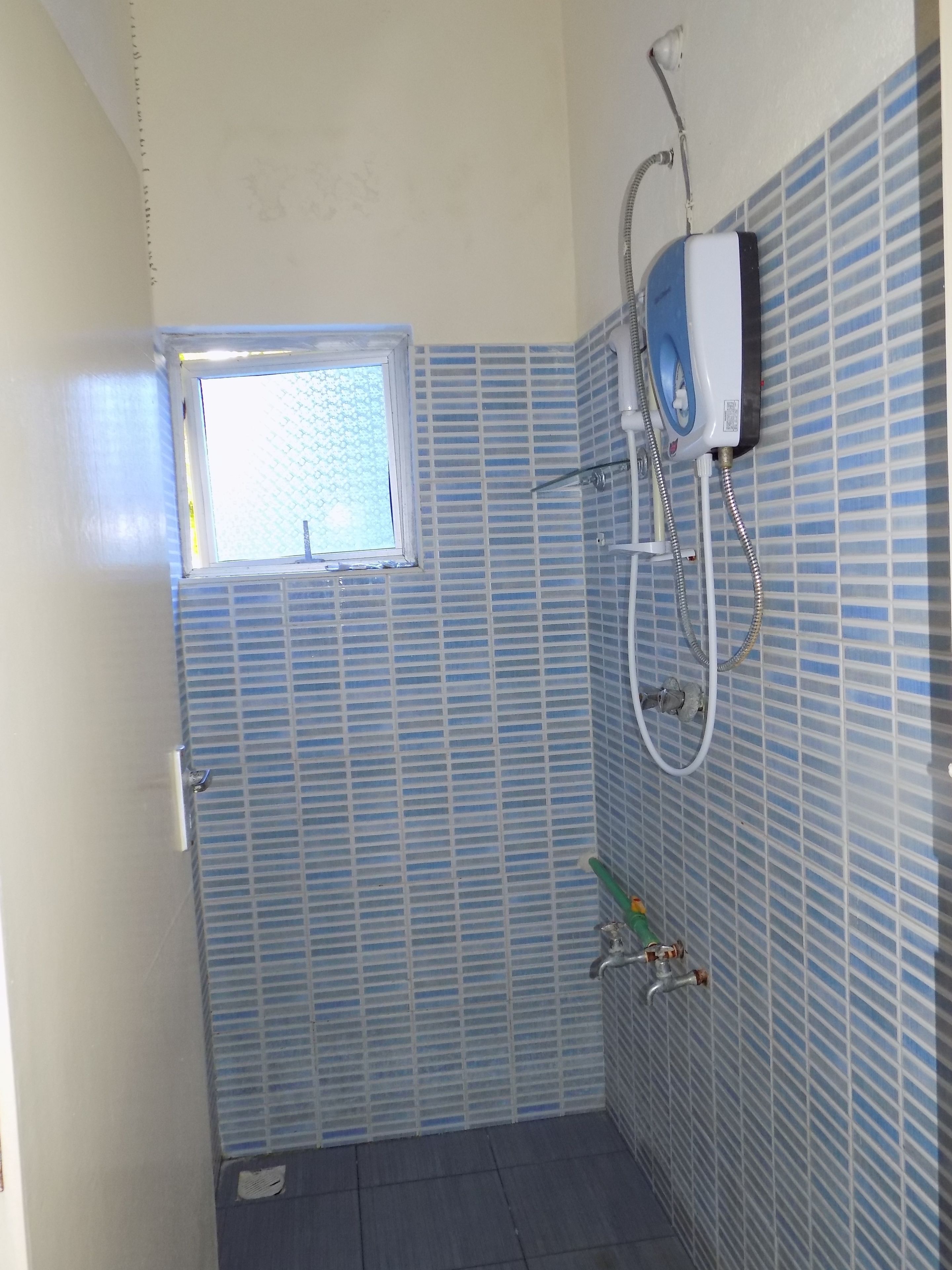 Um banheiro pequeno com azulejos listrados em azul, uma janela, um chuveiro e um porta-toalhas.