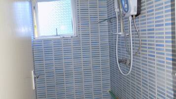Um banheiro pequeno com azulejos listrados em azul, uma janela, um chuveiro e um porta-toalhas.