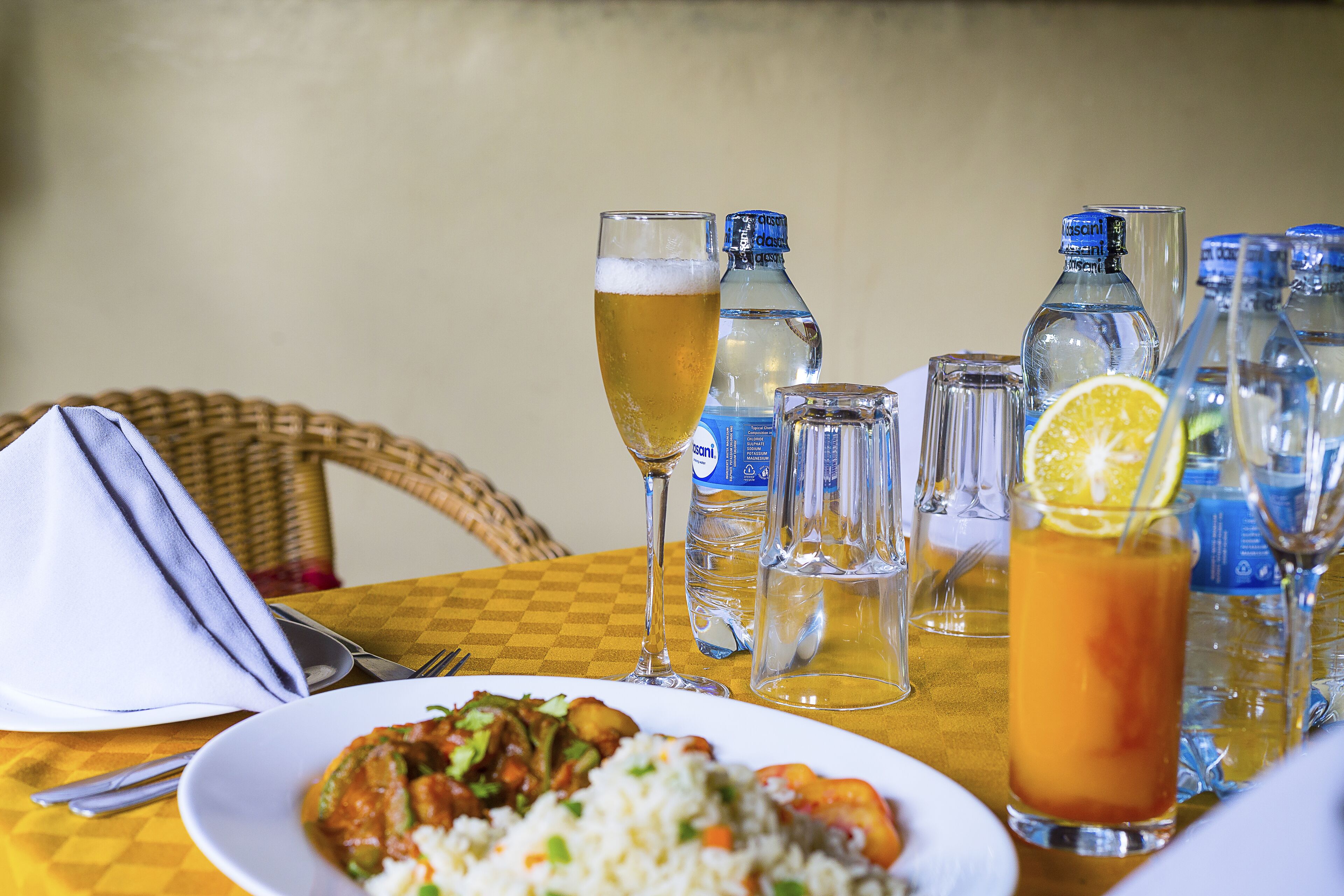 A dining table with a plate of food, glasses, and bottles.
