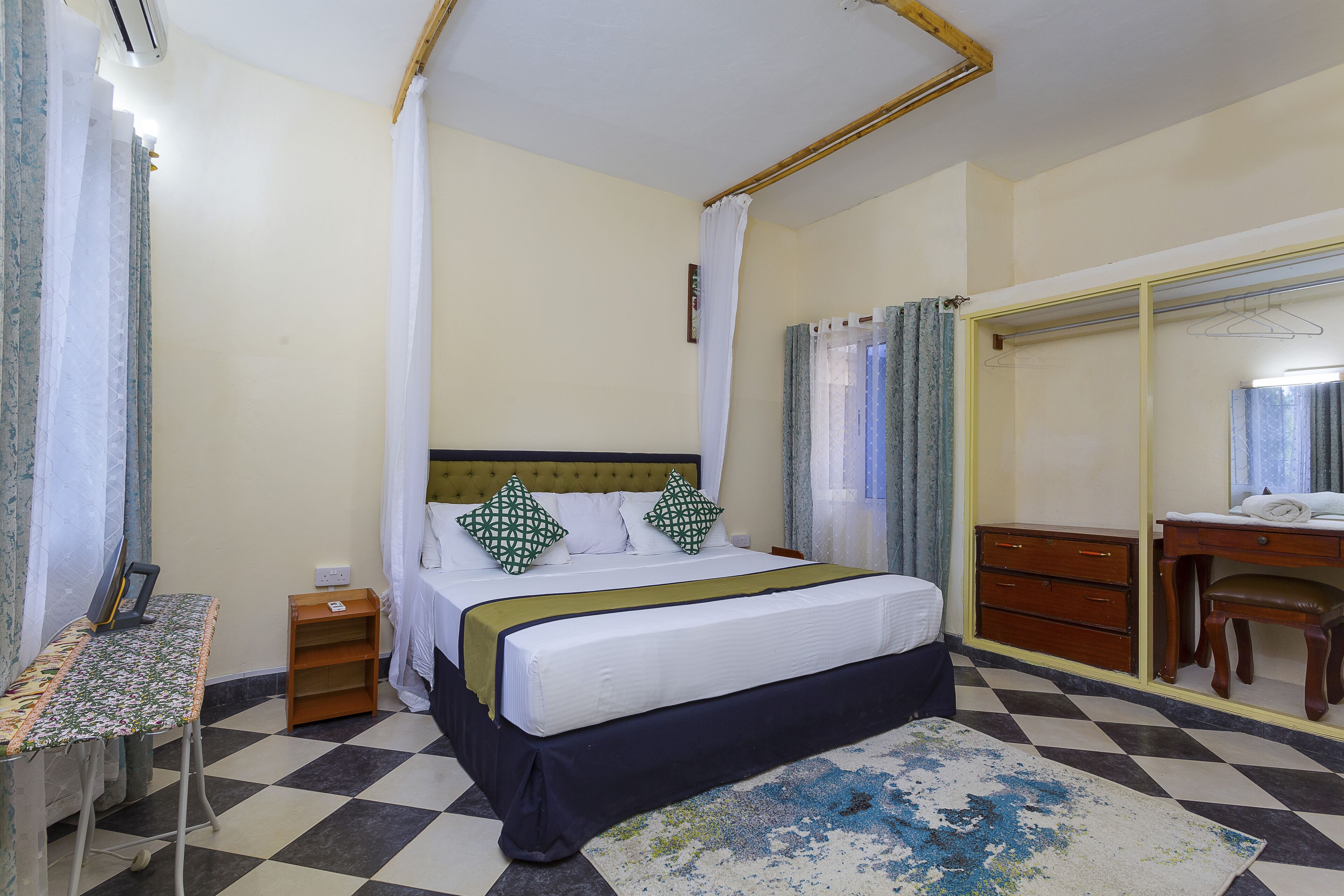 A bedroom with a bed, bedside table, dresser, and a mirror.