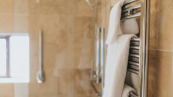 Un baño con toallero y cabezal de ducha.