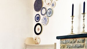 Una silla con un cojín a rayas, una pared adornada con platos decorativos y una chimenea de piedra.