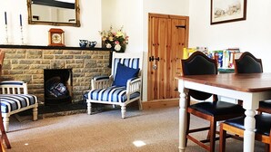 Una sala de estar acogedora con chimenea, un sillón a rayas, una mesa de comedor de madera y sillas a juego.