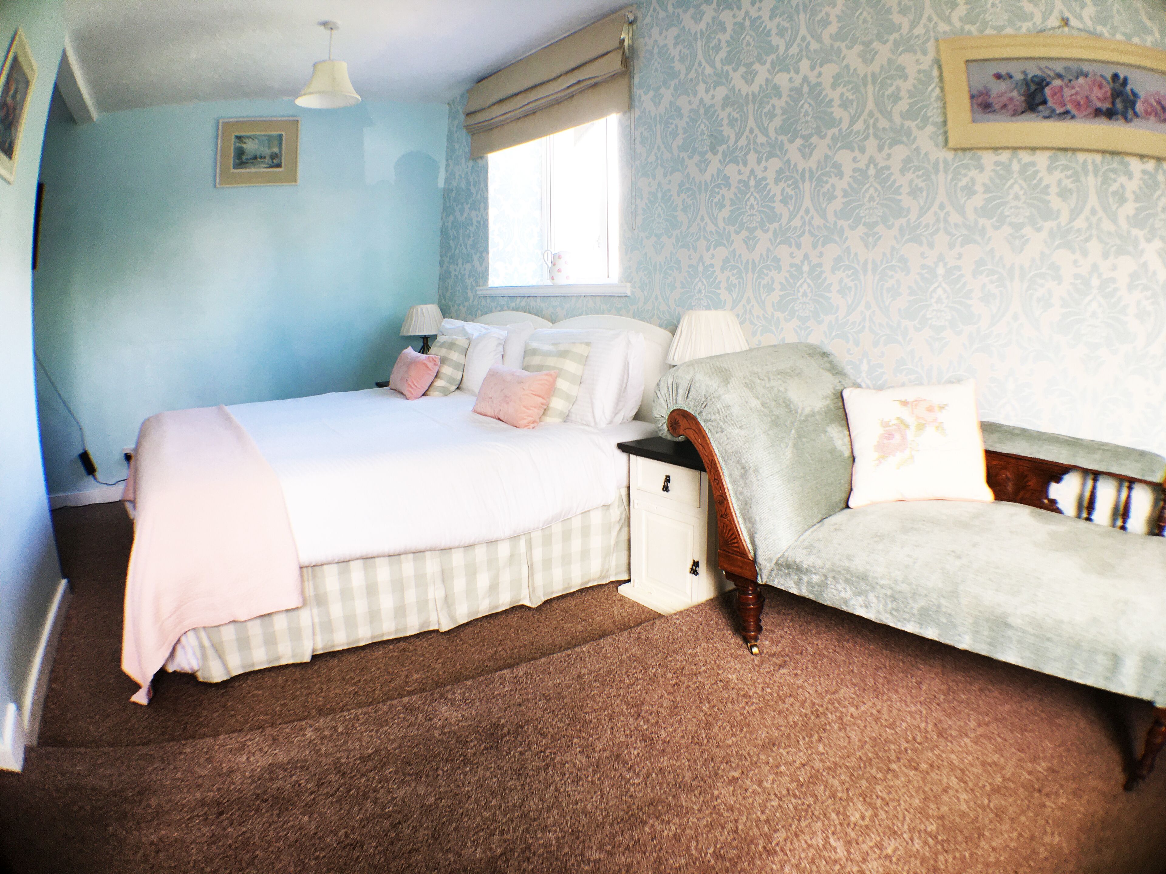 A bedroom with a bed, nightstand, and a chair.