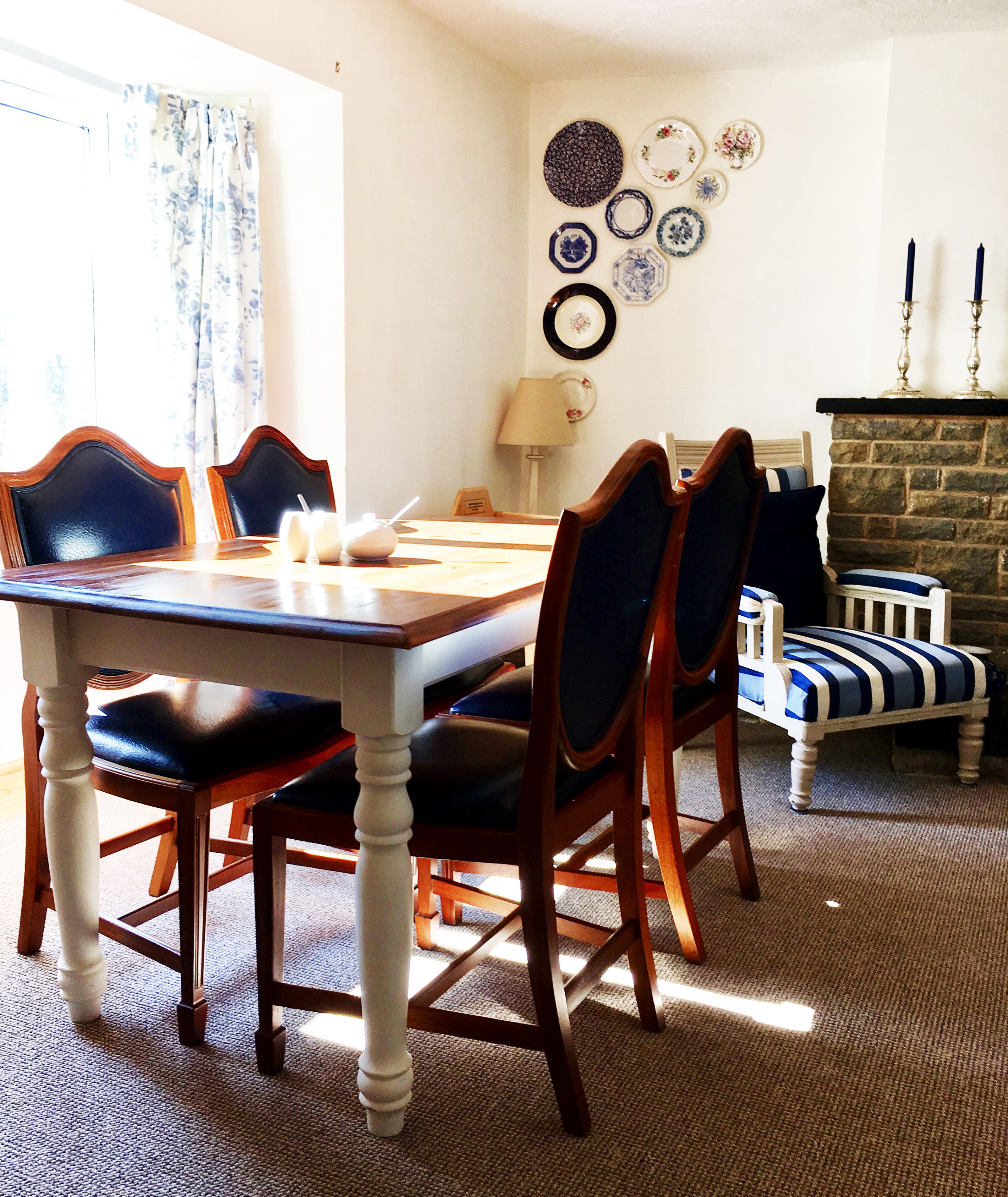 A dining area with a wooden table and chairs, a lamp, and a fireplace.