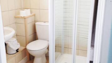 A small bathroom with a toilet, sink, and shower stall.