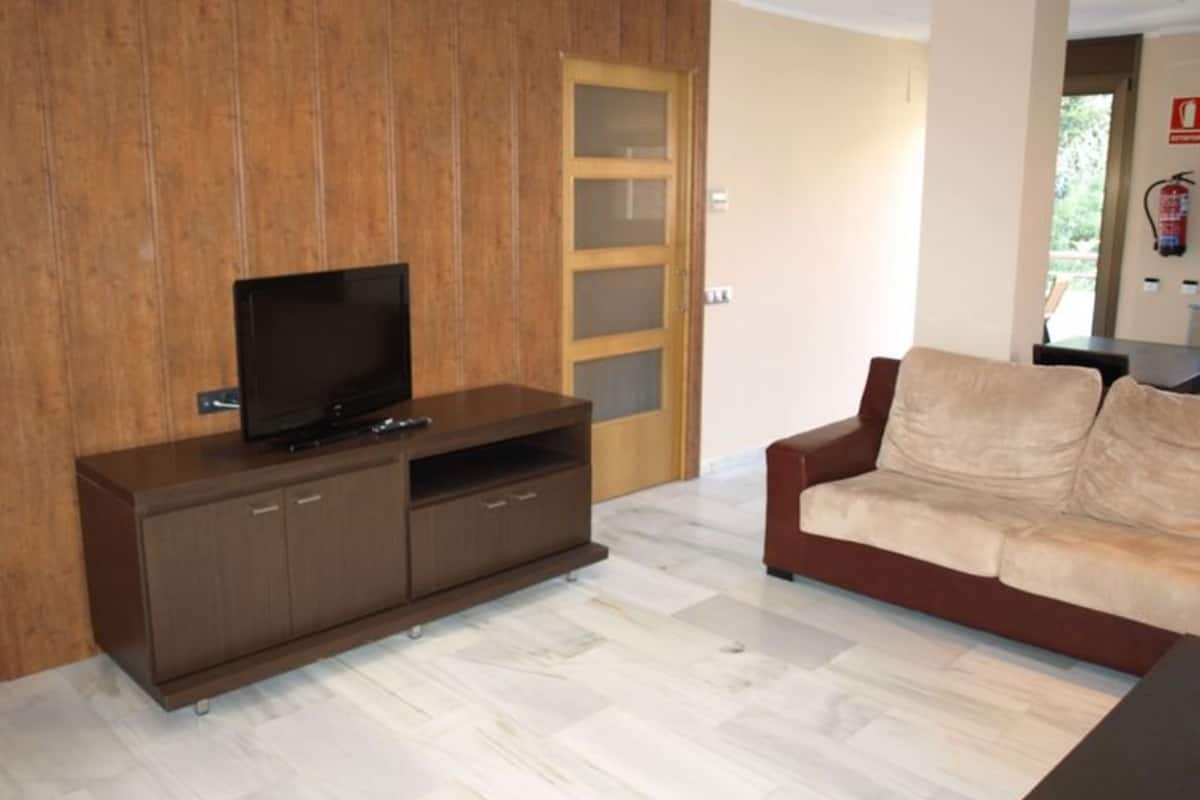 A living room with a wooden cabinet, a television, and a beige sofa.