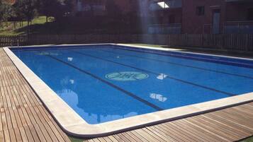 Una piscina rectangular con una cubierta de madera alrededor.