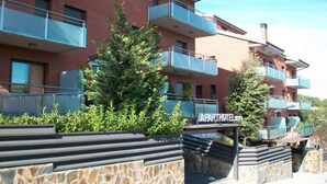 Un edificio de apartamentos de varios pisos con balcones, fachada de piedra y un cartel que indica que es un hotel-apartamento.
