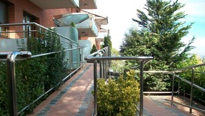 Un sendero de losas de piedra que lleva a un edificio con balcón de vidrio y barandillas de metal.