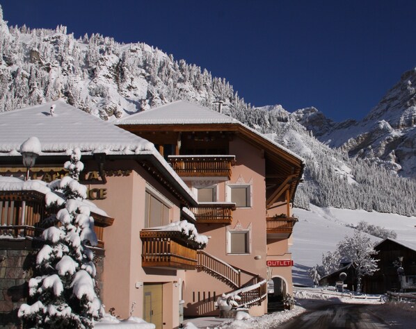 A snow-covered building with a balcony and a sign that reads "OUTLET".