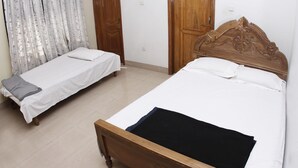 Une chambre avec deux lits simples, des têtes de lit en bois et un sol carrelé.