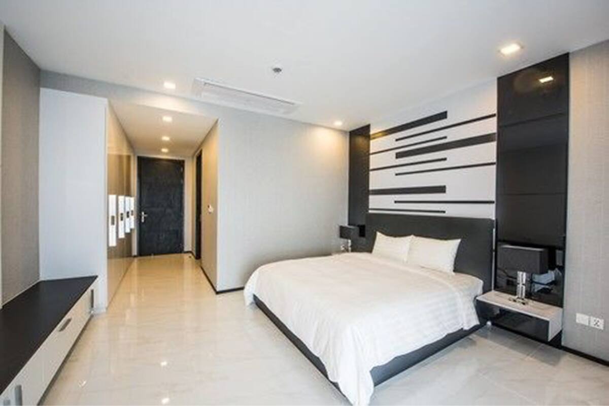 Une chambre d’hôtel moderne avec un grand lit, une table de chevet et un téléviseur fixé au mur.