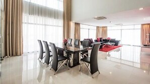A spacious room with a large dining table, black chairs, and a red rug. - Maline Exclusive Serviced Apartments (Phnom Penh)