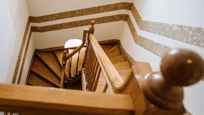 Un escalier en bois, doté d’une rampe et d’un luminaire en haut.