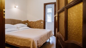 Une chambre à coucher comprenant un lit, une table de chevet, une lampe fixée au mur et une porte donnant sur un balcon.