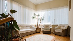 Un salon avec un canapé beige, deux fauteuils, une table basse et une plante en pot.