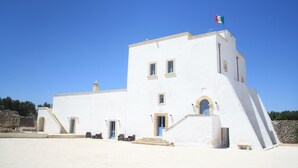 A white building with a flag, a staircase, and a stone wall. - Antica Masseria Torre Mozza (Mesagne)