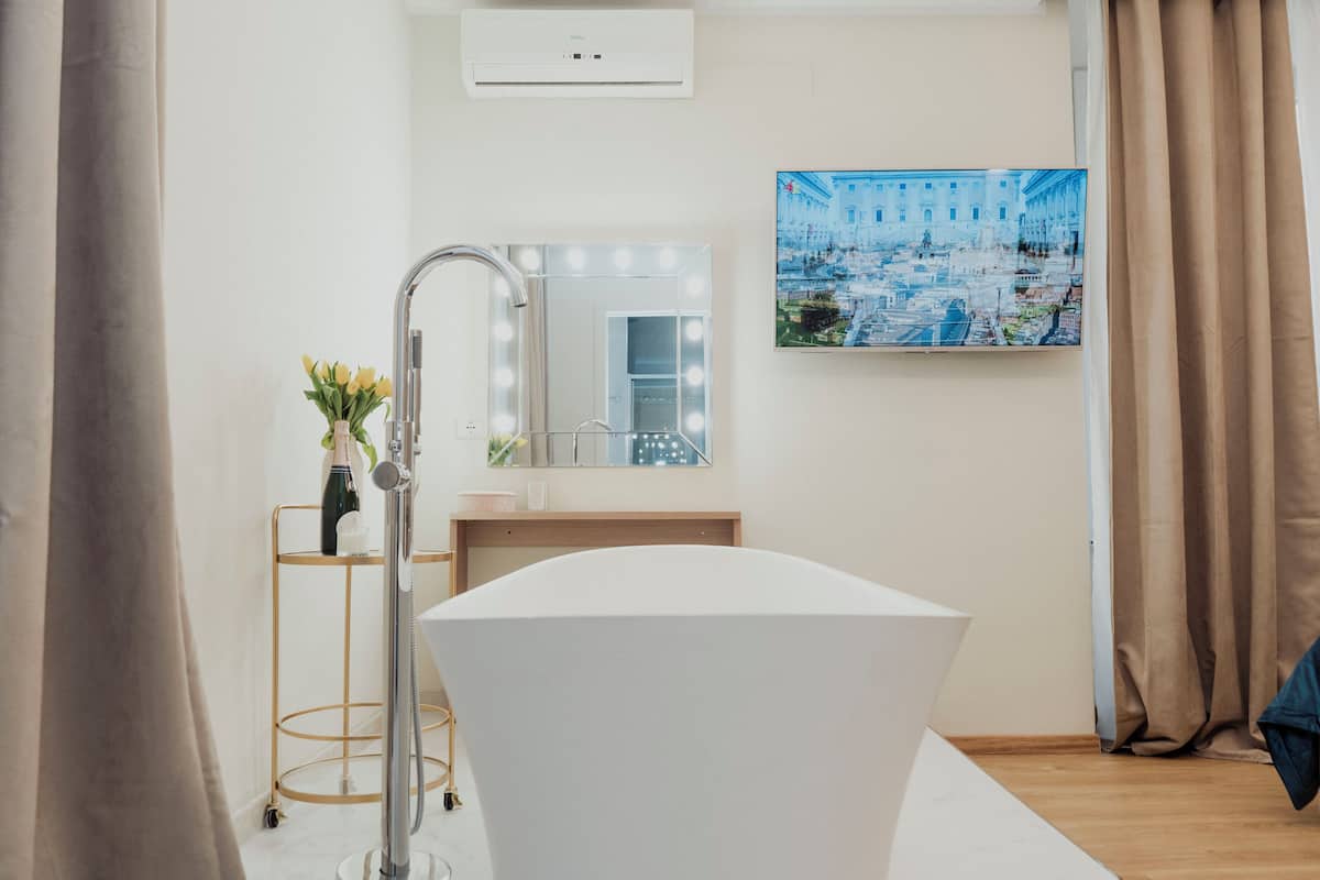 A modern bathroom with a freestanding bathtub, a vanity with a mirror, and a wall-mounted air conditioner.