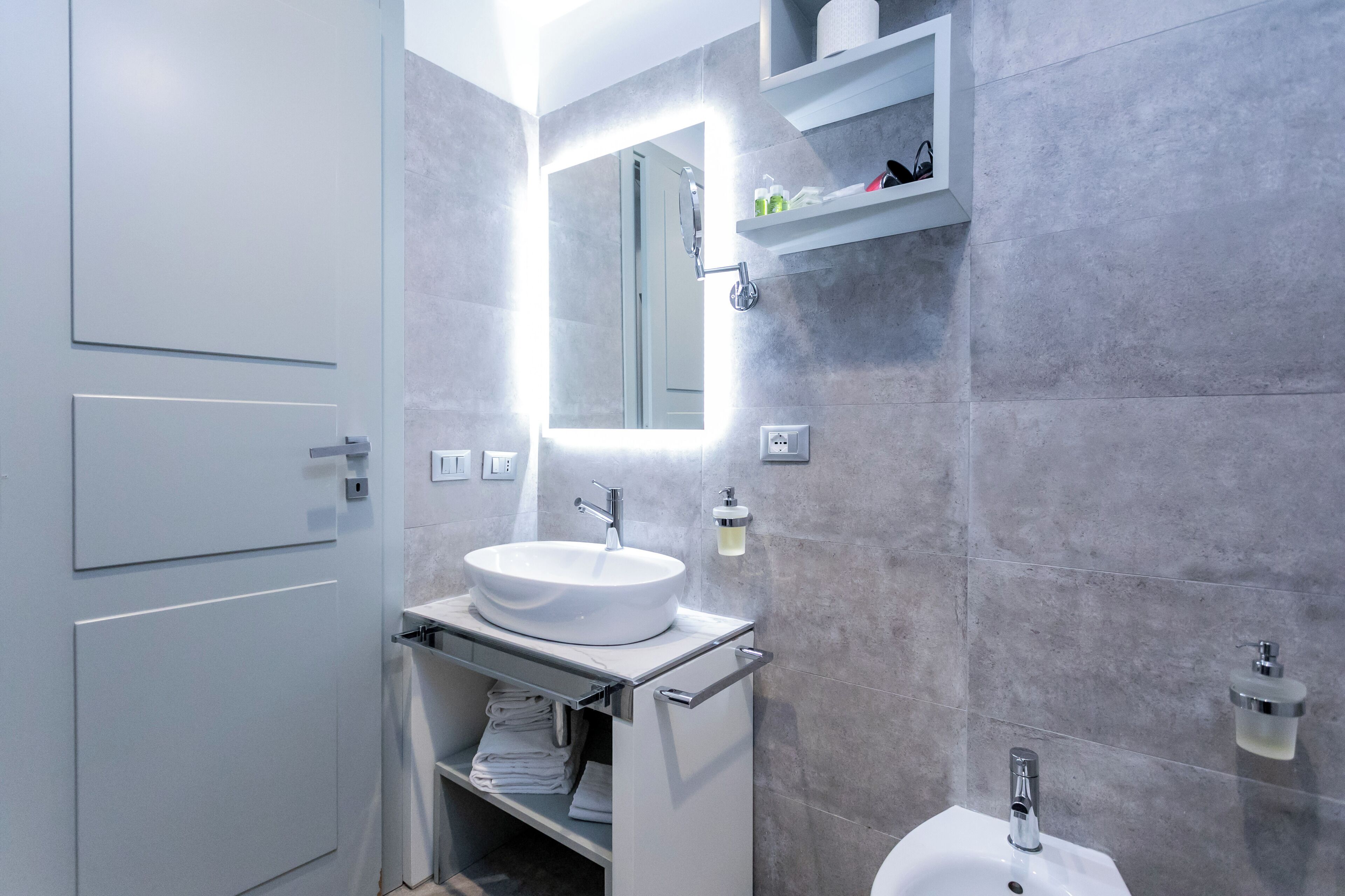 A modern bathroom with a white sink, a mirror, and a shower area.