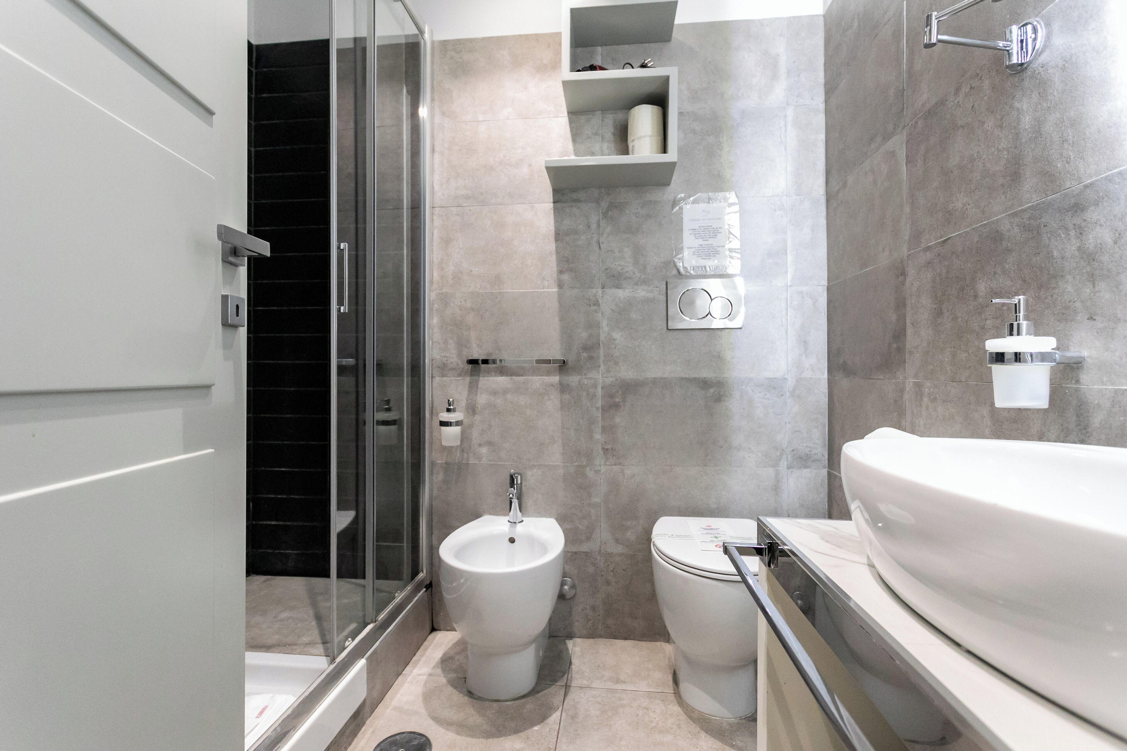 A modern bathroom with a glass shower enclosure, a bidet, and a toilet.