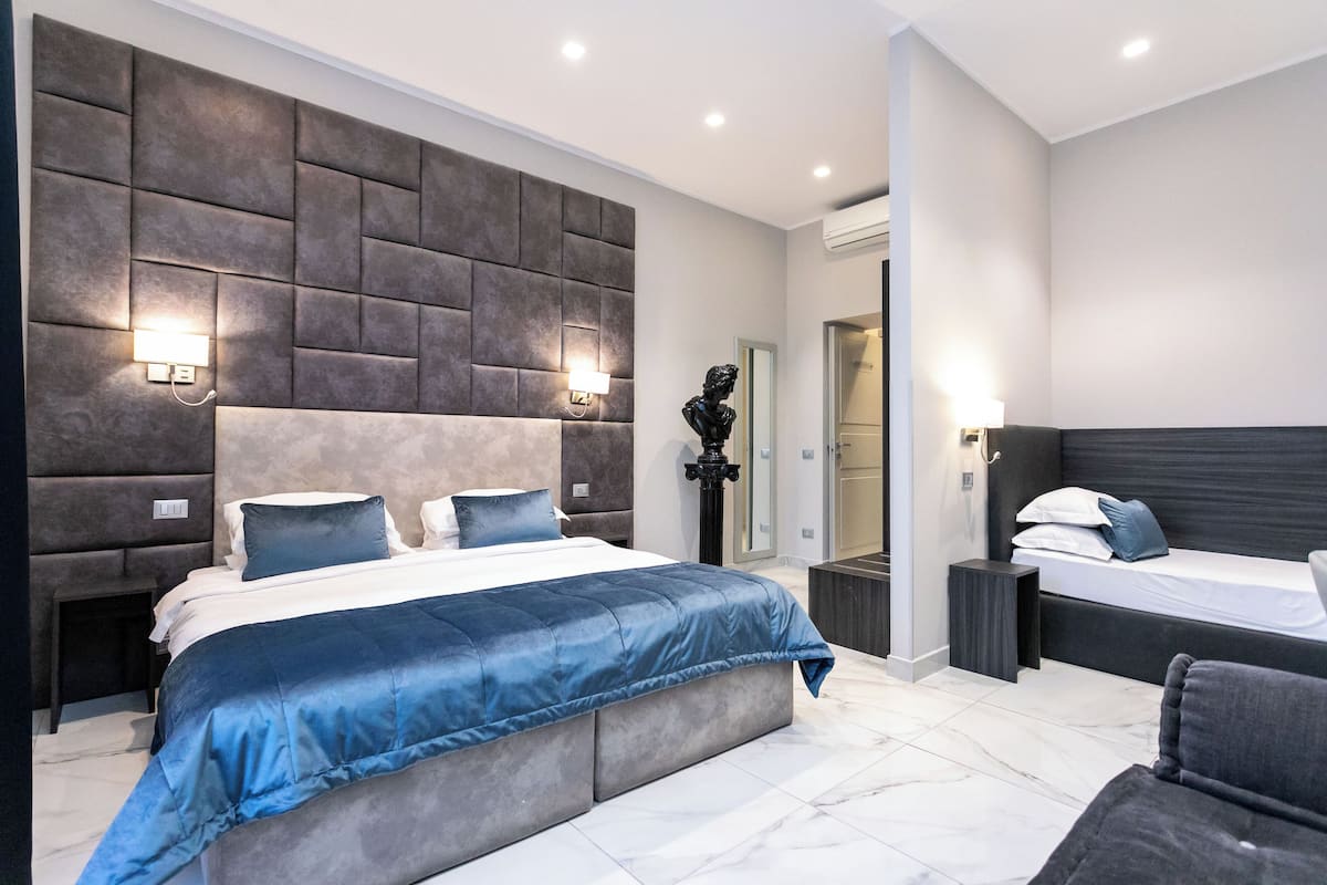 A modern bedroom with a large bed, a smaller bed, and a seating area.