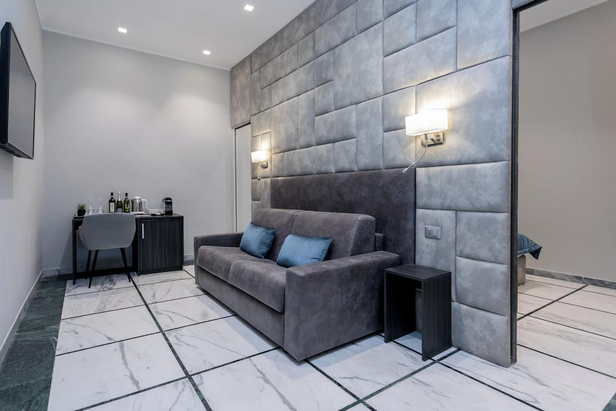 A modern living room with a grey sofa, a small side table, a dark cabinet, and a wall-mounted TV.