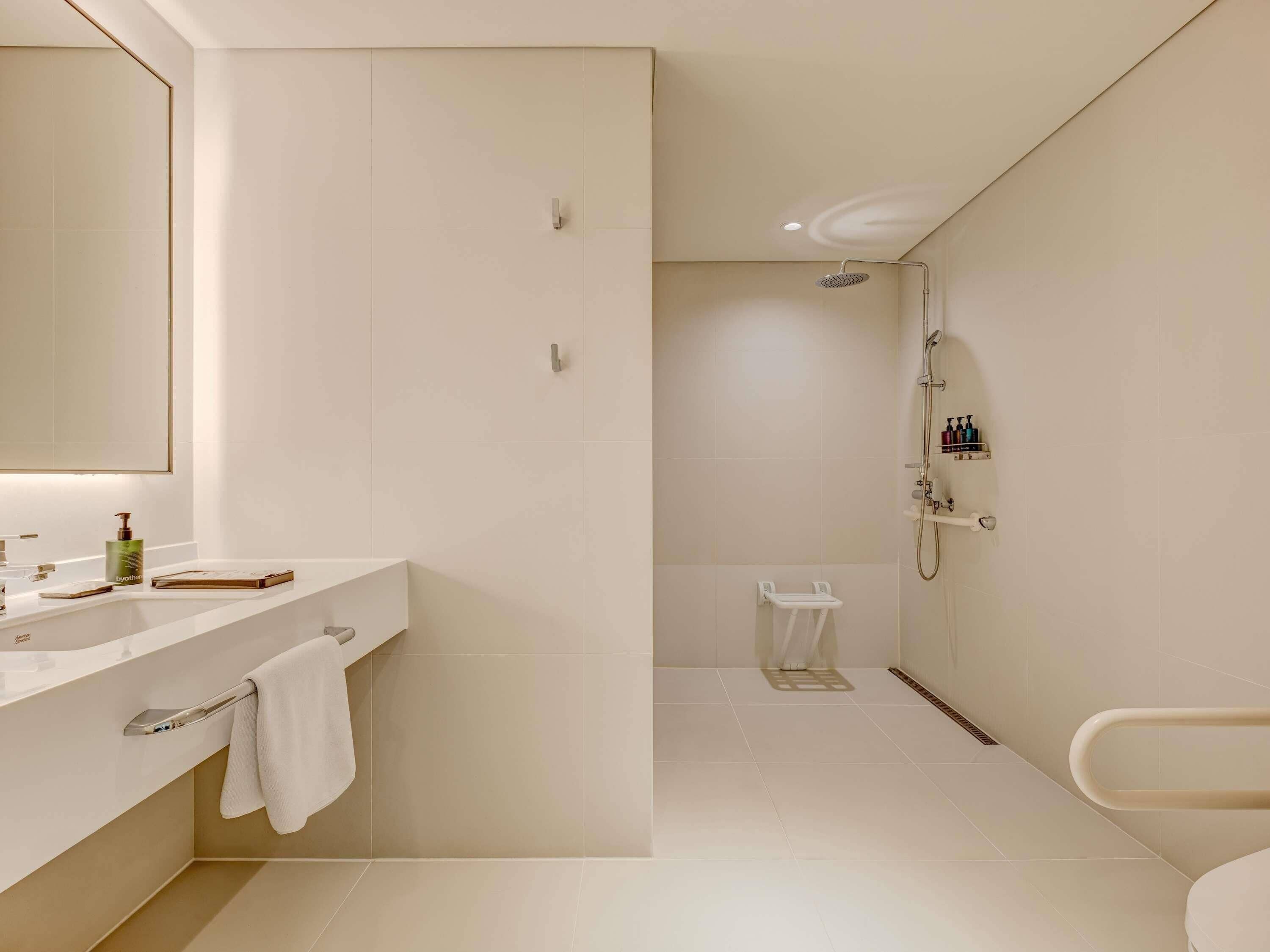 A modern bathroom with a large mirror, a sink, and a shower area.